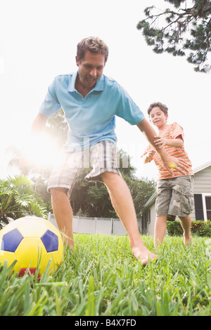 Padre e figlio che giocano a calcio nel cortile posteriore Foto Stock