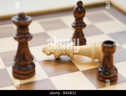 Pezzi di scacchi che circonda re decaduto Foto Stock