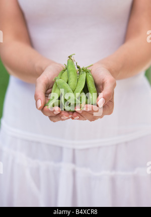 Donna che mantiene i piselli freschi Foto Stock