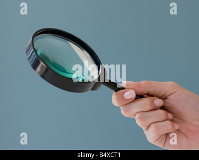 Stretta di mano che tiene la lente di ingrandimento Foto Stock