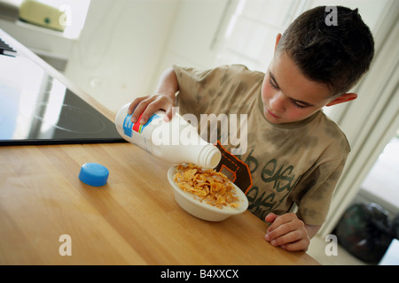 Ragazzo versando il latte nella tazza di fiocchi di mais Foto Stock