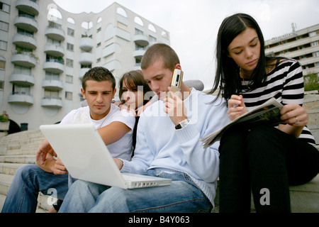Giovani uomini e donne che utilizzano computer portatile e il telefono cellulare Foto Stock