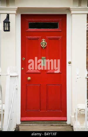 Porta anteriore di colore rosso brillante con cassetta portone in ottone e un batticalcagno e gradino. Inghilterra (41) Foto Stock