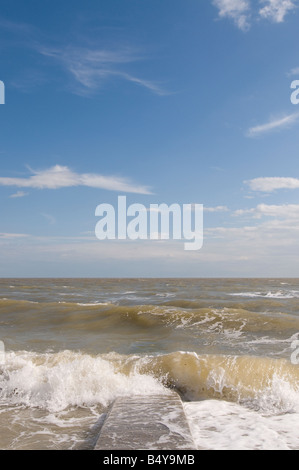 Onde che si infrangono sulle groyne in calcestruzzo Foto Stock