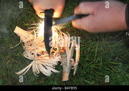 Utilizzando un incendio di acciaio per incendiare bastoncini di piuma per creare il fuoco Foto Stock