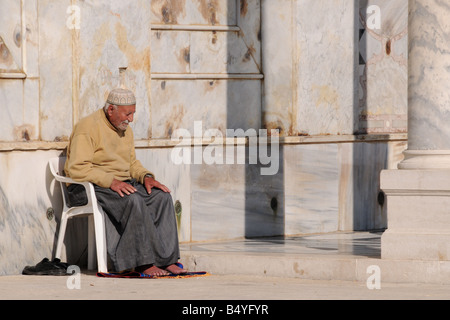 Un uomo anziano si siede da solo nella preghiera al di fuori della Cupola della roccia di Gerusalemme's Temple Mount/Haram al-Sharif. Foto Stock