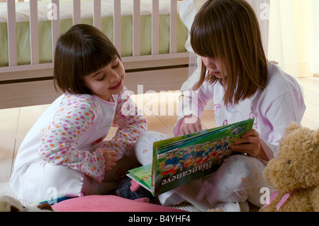 Bambine la lettura di un libro, pigiama Foto Stock