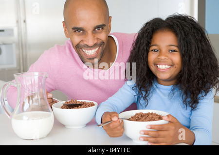 Padre seduto con la figlia come lei devono mangiare la prima colazione Foto Stock