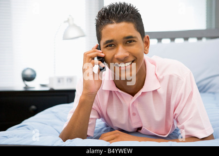 Ragazzo adolescente sdraiato sul letto tramite telefono cellulare Foto Stock