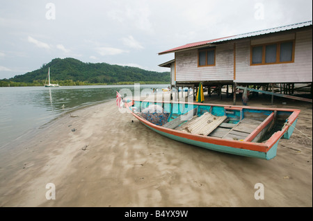 Barca da pesca e casa di pescatori sulle sponde della foce del fiume Santubong nr Kuching Sarawak Malaysia Foto Stock