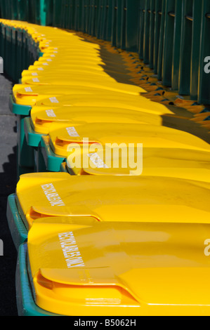 Un sacco di cassonetti per il riciclaggio o scomparti wheelie allineate in una fila con colore giallo brillante coperchi Foto Stock