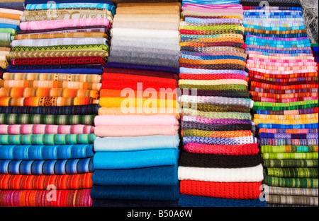 Pile di Andino Peruviano sciarpe, scialli e pashminas piegate ordinatamente per dare una colorata immagine astratta Foto Stock