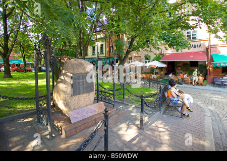 I turisti seduti davanti al memoriale per gli ebrei vittime dell'olocausto in Kazimierz, il quartiere ebraico quartiere di Cracovia. Foto Stock