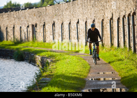 Ciclista a cavallo lungo un canale alzaia Foto Stock