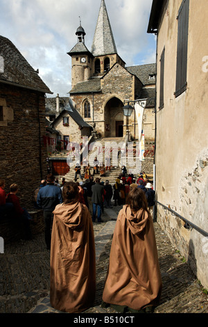 Gli abitanti di un villaggio vestito in costumi medievali guarda i musicisti a Estaing chiesa Foto Stock