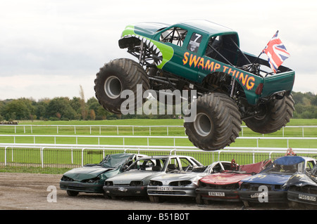 Monster truck saltando su vetture frantumato in una gara Foto Stock