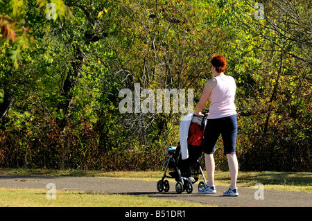 Una giovane madre spinge il suo bambino in un passeggino come lei cammina per esercitare sul pubblico di percorsi a lago Hefner, Oklahoma City. Foto Stock