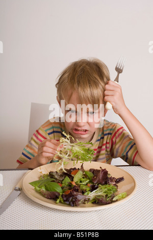 Ragazzo che rifiuta di mangiare insalata Foto Stock