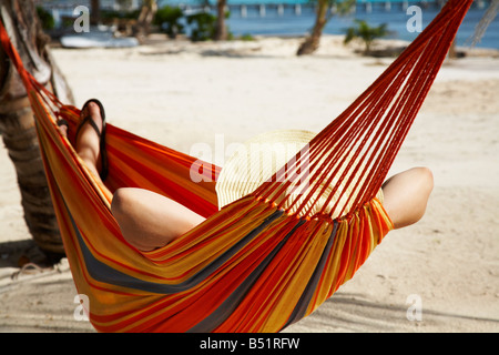 Donna sdraiata in amaca sulla spiaggia Foto Stock