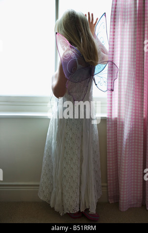 Giovane ragazza a guardare fuori dalla finestra Foto Stock