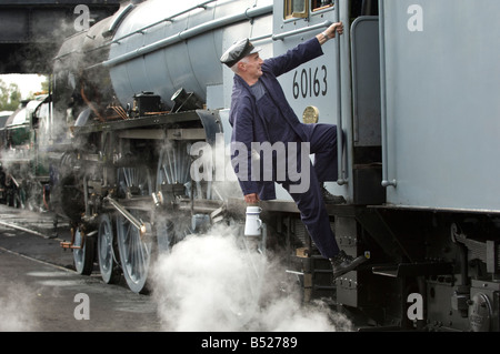 Un motore a vapore guidatore sale nella sua cabina. Il treno è 60163 Tornado, sulla Grande Stazione Centrale. Foto Stock