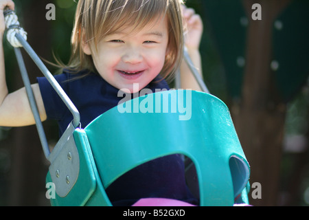 Un 2-anno-vecchia ragazza toddler gode di oscillazione. Foto Stock