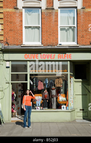 Una donna si erge al di fuori "Oliva Alfie ama' kid's lifestyle boutique e negozio di abbigliamento in Church street a Stoke Newington Hackney Foto Stock
