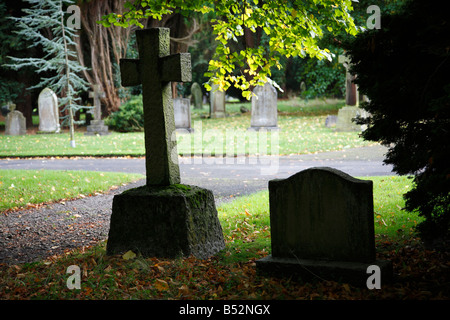 Testa Croce di pietra retroilluminato in cimitero con fogliame di autunno in autunno. Cimitero di Carlisle, Dalston Road, Carlisle, Cumbria, Regno Unito. Foto Stock