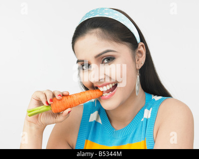 Una smart donna asiatica di origine indiana di mangiare una carota Foto Stock