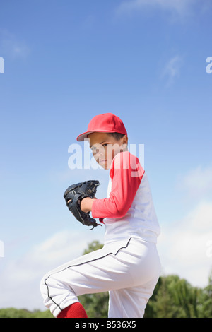 Razza mista ragazzo in uniforme da baseball pitching nel gioco Foto Stock