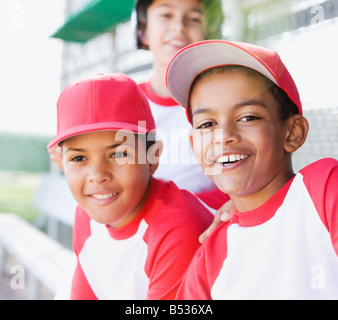 Multi-etnico boys in baseball uniformi sorridente Foto Stock