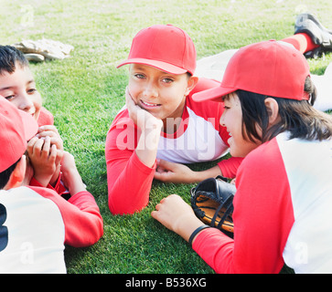 Multi-etnico boys in baseball uniformi che posa in erba Foto Stock