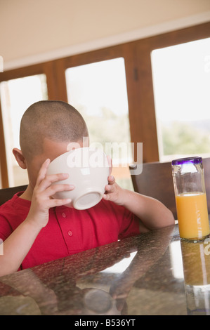 Ragazzo ispanico bere latte dalla ciotola di cereali Foto Stock