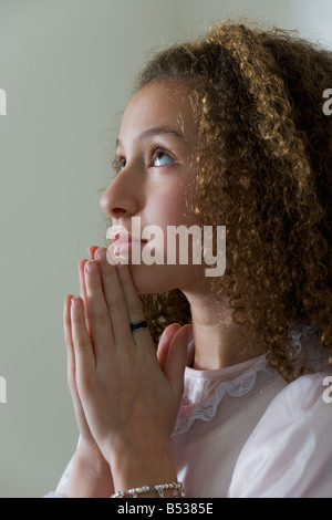 Razza mista ragazza in nightgown pregando Foto Stock