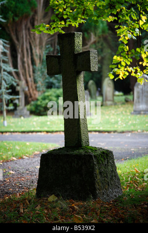 Testa Croce di pietra retroilluminato in cimitero con fogliame di autunno in autunno. Cimitero di Carlisle, Dalston Road, Carlisle, Cumbria, Regno Unito. Foto Stock