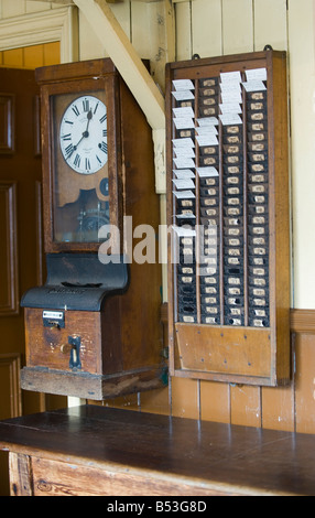 Clocking sulla macchina e schede di tempo sulla parete di fabbrica Foto Stock