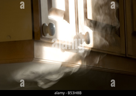 Soffietto di fumo fuori da sotto un armadio Foto Stock