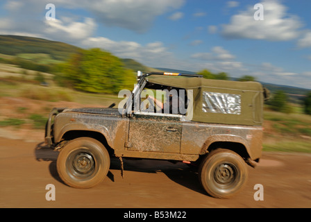 Terreni fangosi Land Rover Defender 90 Softtop accelerando su una pista forestale nel Weserbergland. Foto Stock