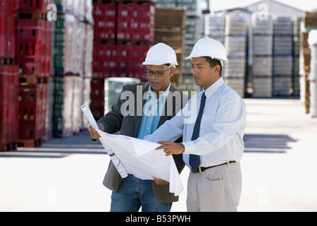 Architetti rivedendo blueprint in fabbrica Foto Stock