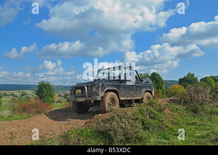 Terreni fangosi Land Rover Defender 90 Softtop guidando lungo una pista forestale nel Weserbergland. Foto Stock