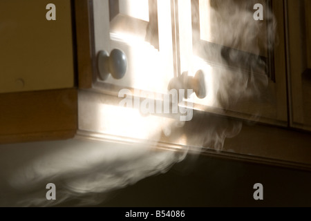 Soffietto di fumo fuori da sotto un armadio Foto Stock