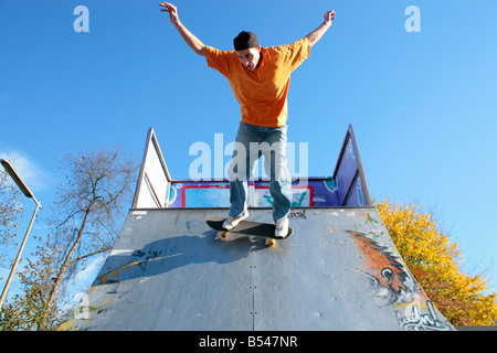 Giovane uomo a cavallo su un trimestre con il suo skateboard Foto Stock