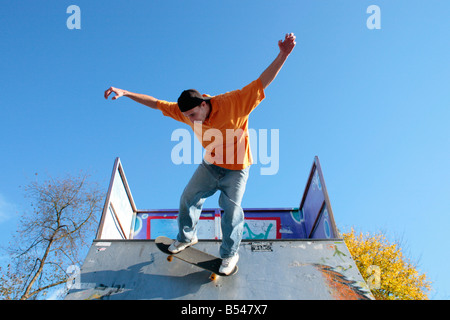 Giovane uomo a cavallo su un trimestre con il suo skateboard Foto Stock