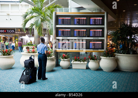 Femmina assistente di volo guardando la data di arrivo e di partenza la pianificazione all'Aeroporto Internazionale di Orlando Foto Stock