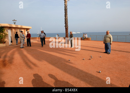 Lunghe ombre attraversano il campo mentre gli uomini giocano a Antibes, nel sud della Francia. Uomini francesi maschi tempo libero amici passatempo stile di vita scena di strada Foto Stock