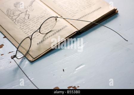 In vecchio stile gli occhiali da lettura sulla parte superiore di un vecchio libro su un tavolo Foto Stock