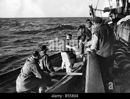 La flotta di pesca aiuta il Navy.. Questi Peschereccio gli uomini credono che una buona volta merita un altro e qui nel Mare del Nord sono visto passare un paio di ceste di pesce per alcuni di un equipaggio di un dragamine britanniche (in piccola barca) che ha appena lasciato minesweeper in background. Basta un po' di apprezzamento per gli uomini che per spazzare via le mine vaganti ecc nel Mare del Nord e a rendere più sicura la pesca. Novembre 1942 P012252 Foto Stock