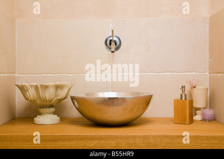 Elegante e moderno lavello in acciaio con alcuni accessori in una bella sala da bagno Foto Stock