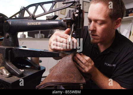 Un uomo utilizza un antico Singer macchina per cucire per la riparazione di prodotti in pelle in un piccolo negozio in Maryland USA Foto Stock