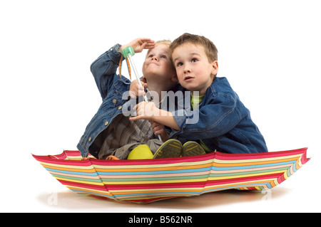 Due ragazzi seduti in un ombrello come esso s una barca che ri guarda se la tempesta è in arrivo Foto Stock